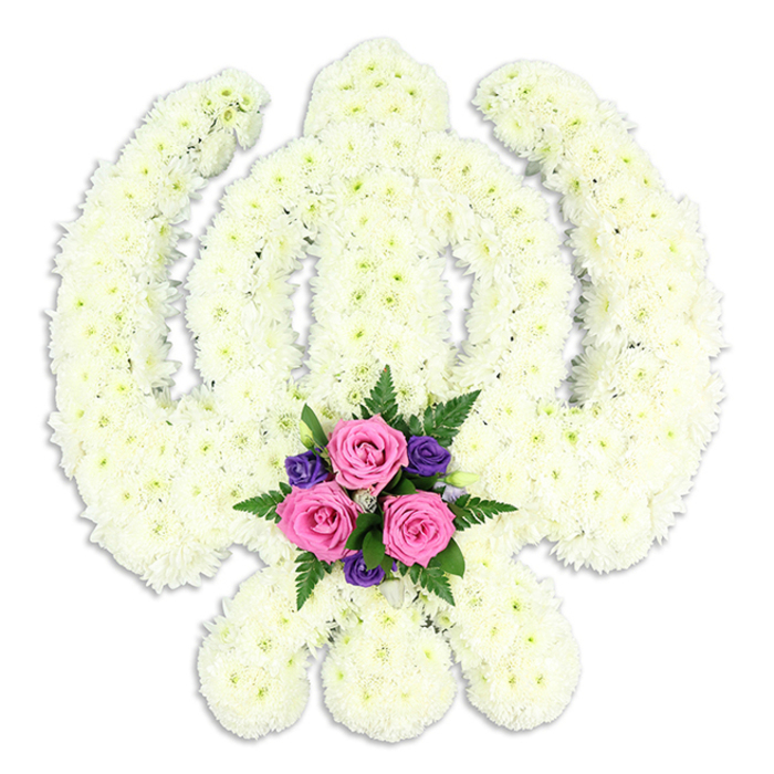 A reverent Sikh Khanda funeral tribute stands out crisply against a flawless white background, its entire structure crafted from a carpet of white chrysanthemum florets that fit together like tiny, soft tiles. The central double-edged sword rises straight and true, framed by the circular chakkar, while the two curved kirpans sweep symmetrically to each side, all rendered with remarkable precision in blooms that appear freshly cut and expertly conditioned. Each chrysanthemum head shows layers of fine petals radiating from a gentle cream centre, giving the piece a plush, velvety surface that seems almost touchable. The calm, neutral tones evoke a sense of purity and peace, reminiscent of a quiet morning walk through the residential streets of Raynes Park or Colliers Wood. At the very base of the Khanda, where the kirpans cross, a compact cluster of accent flowers breaks the expanse of white with a meaningful touch of colour. Three rich pink roses form the heart of this grouping, their petals tightly wrapped yet softly curved, suggesting both strength and tenderness. Around them nestle smaller, deep purple blooms-perhaps freesias or lisianthus-interwoven with fine, feathery fern fronds and polished green foliage. This subtle bouquet within the larger design adds depth and visual balance, like a heartfelt message whispered within a formal tribute. The piece casts a faint, diffused shadow on the surface below, giving it weight and presence, as if ready to be delivered to a gurdwara or family home in Merton for a final farewell. Created with the care and skill of experienced local florists, this Khanda arrangement embodies devotion, respect, and the unbroken continuity of Sikh faith and tradition.